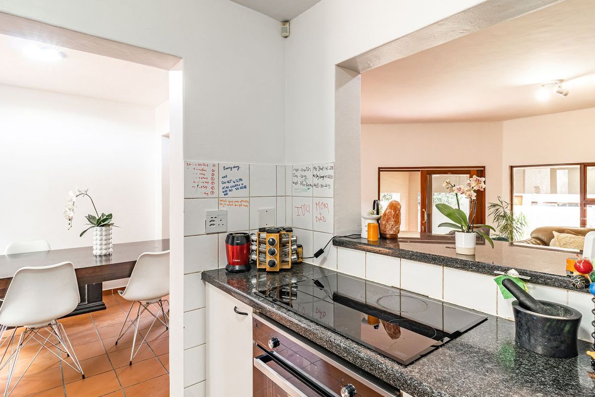 A functional kitchen featuring granite countertops, a built-in oven, and an electric hob, with a convenient pass-through window connecting to the dining area.