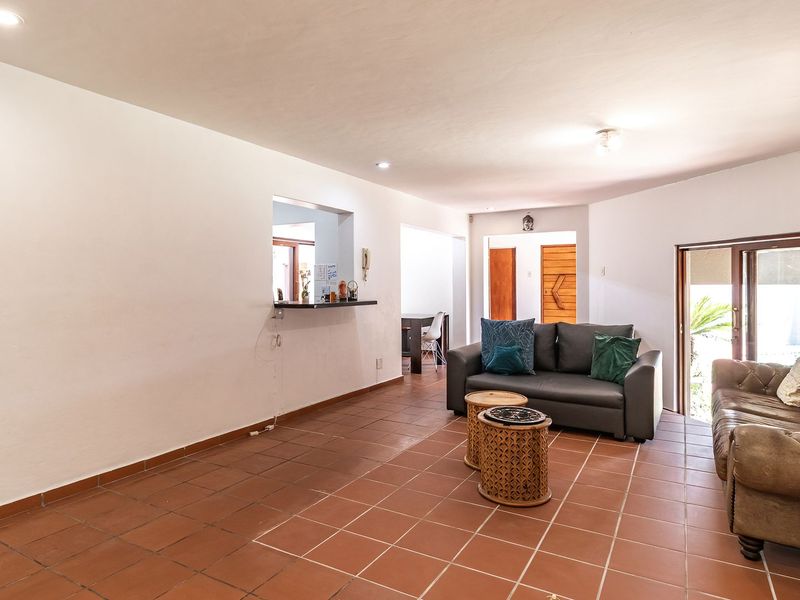 Spacious living area featuring terracotta floor tiles, recessed lighting, and a convenient serving hatch connecting to the kitchen area.