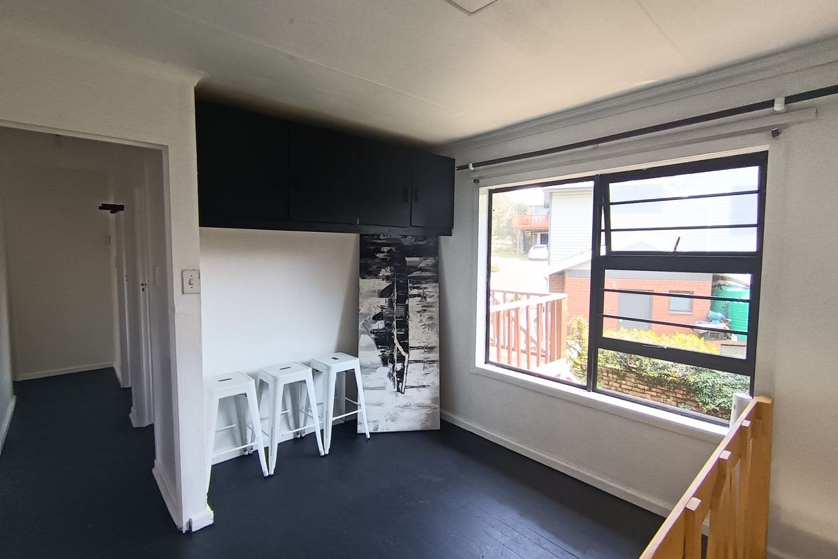 A living area featuring built-in overhead storage, timber window frames, and a timber balustrade overlooking the lower level.