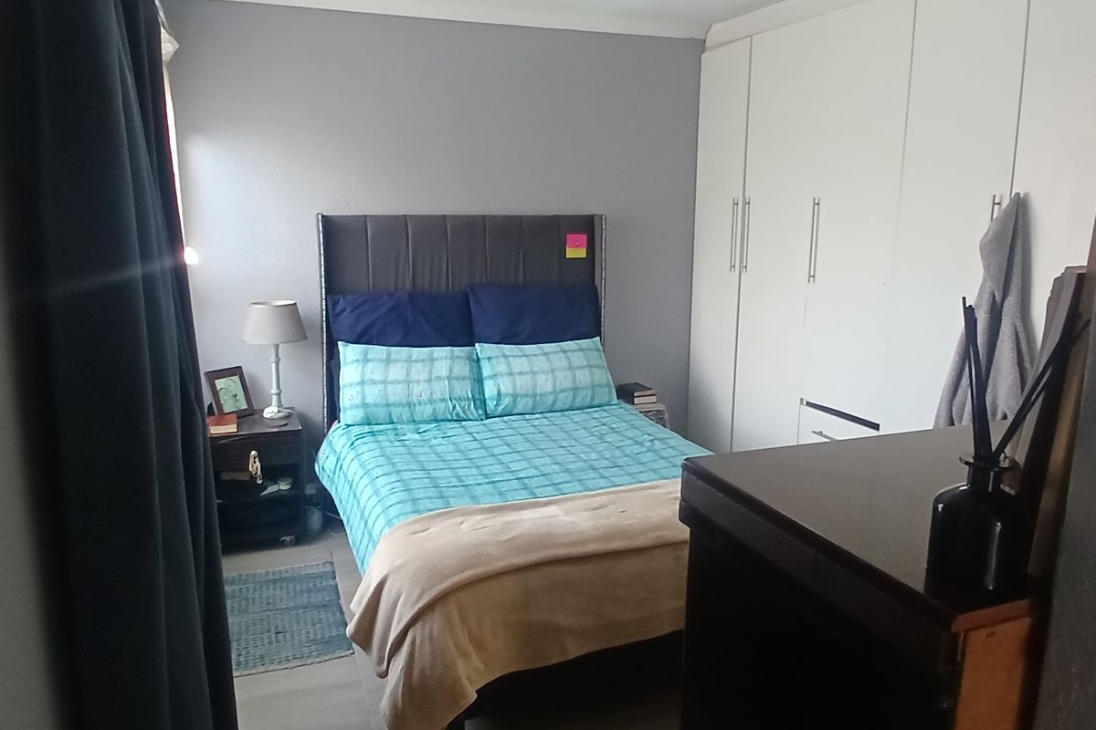 A functional bedroom featuring built-in cupboards and neutral wall finishes, providing a comfortable and practical sleeping space.