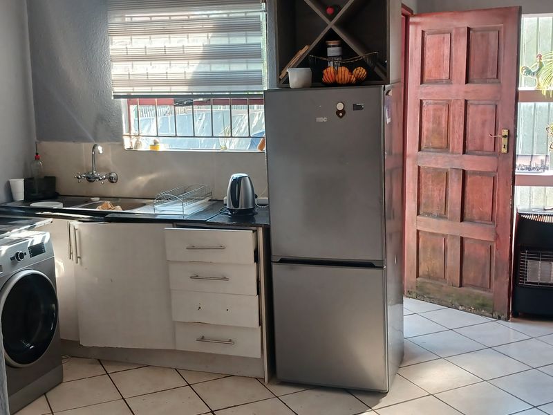 Compact kitchen area featuring tiled flooring, built-in cabinetry, and direct access to the exterior through a timber door.