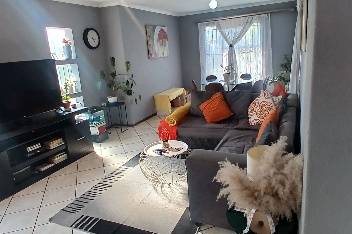 A comfortable living room featuring tiled flooring and built-in wall niches, providing a functional and well-lit space for relaxation.