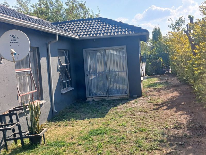 Rear view of the house featuring a tiled roof, sliding glass doors, and a garden area with established hedging.