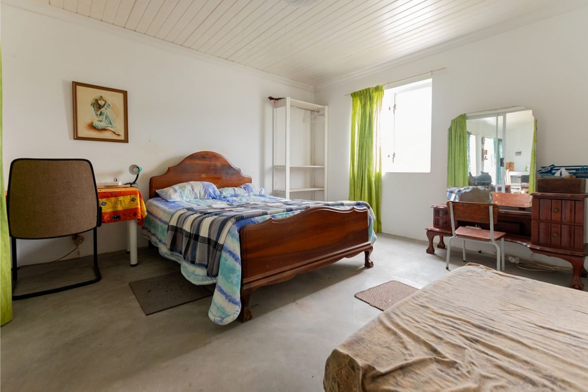 A bedroom featuring a tongue and groove ceiling, casement window, and exposed concrete flooring, offering a blank canvas for renovation and interior updates.