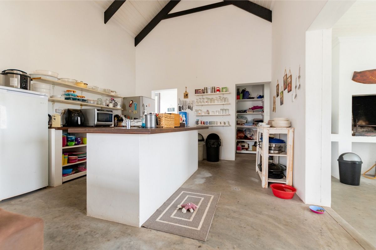 Spacious kitchen featuring a central island, vaulted ceilings with exposed beams, concrete flooring, and an integrated fireplace, offering a rustic and functional layout.