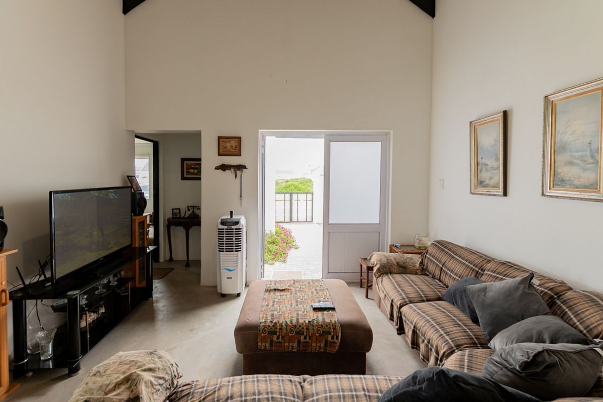 Spacious living room featuring high vaulted ceilings with exposed beams, polished concrete flooring, and direct access to an outdoor patio area.
