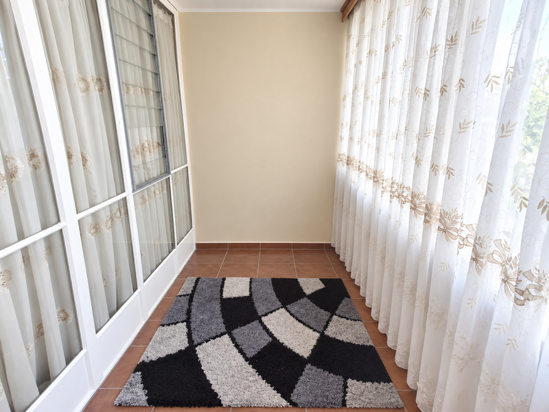A bright, enclosed balcony or sunroom featuring tiled flooring, large glass sliding doors, and louvre windows, offering a versatile space for relaxation.