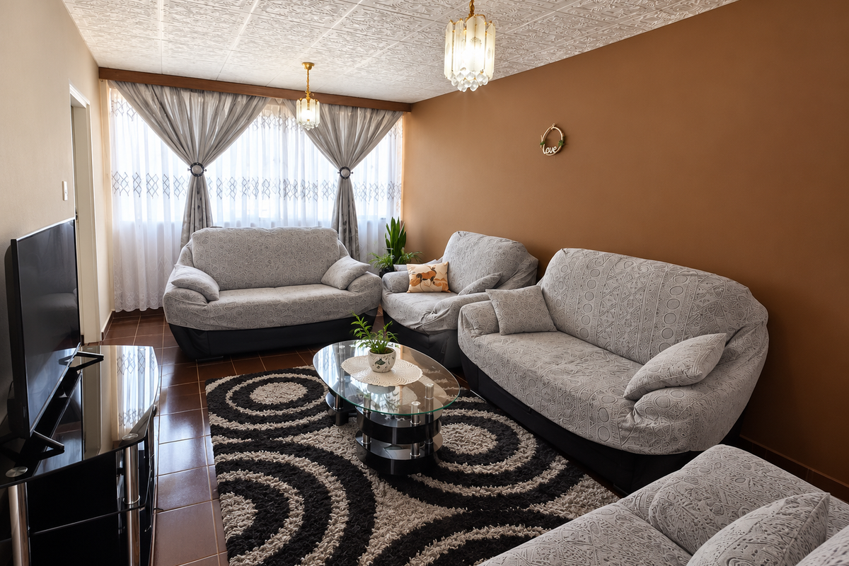 A comfortable living room featuring tiled flooring, a decorative textured ceiling, and warm-toned walls, providing a cozy space for relaxation.