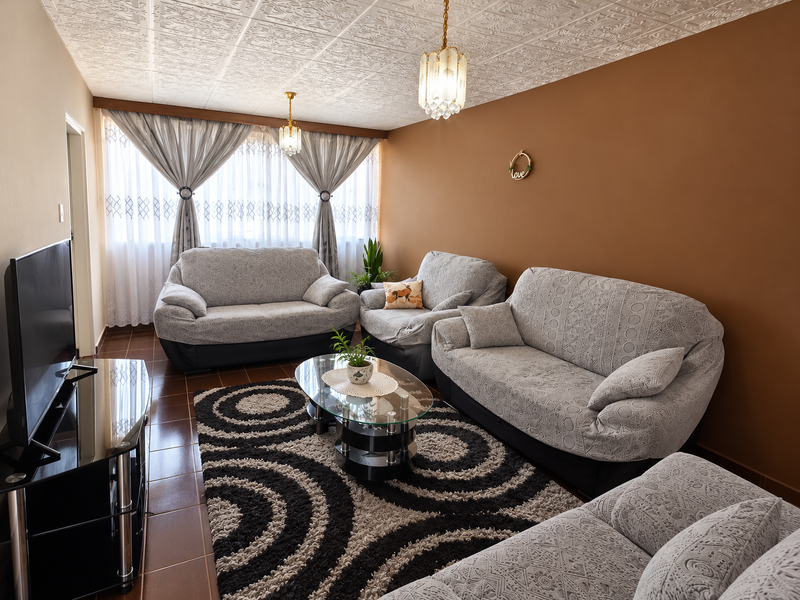 A comfortable living room featuring tiled flooring, a decorative textured ceiling, and warm-toned walls, providing a cozy space for relaxation.