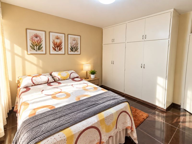 A well-lit bedroom featuring ample built-in cupboard storage and tiled flooring, creating a comfortable and functional living space.