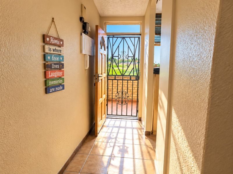 Entrance hallway featuring tiled flooring, an intercom system, and a secure metal gate leading to an outdoor area.