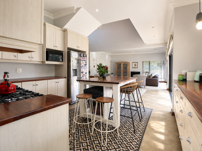 Spacious open-plan kitchen and living area featuring a central island, wooden countertops, gas hob, and vaulted ceilings with abundant natural light.