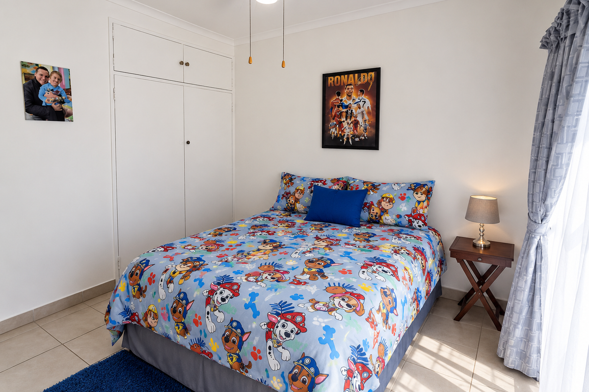 A well-maintained bedroom featuring neutral tiled flooring, a built-in wardrobe, and a ceiling fan, offering a clean and functional living space.