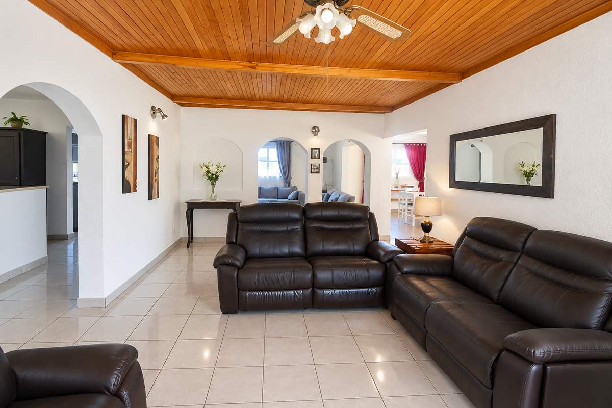 Spacious living room featuring a warm timber-clad vaulted ceiling, neutral tiled flooring, and distinctive arched architectural transitions leading to adjacent living areas.