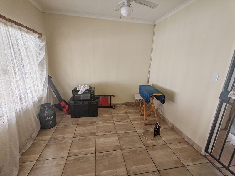 A functional utility space featuring tiled flooring and a ceiling fan, offering a versatile area for laundry or storage needs.