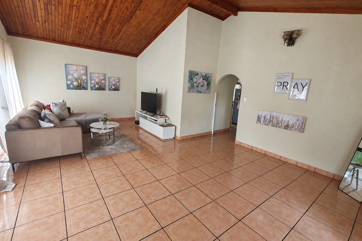 Spacious living room featuring a vaulted timber ceiling, ceramic tiled flooring, and an arched doorway leading to adjacent areas.