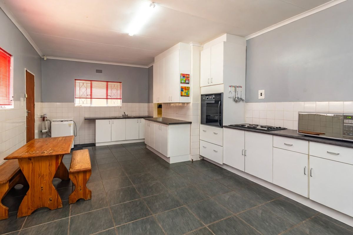 Spacious kitchen featuring white built-in cabinetry, dark laminate countertops, built-in oven, hob, and tiled flooring with a functional layout.