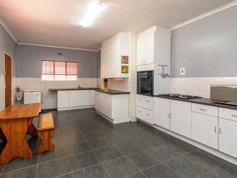 Spacious kitchen featuring white built-in cabinetry, dark laminate countertops, built-in oven, hob, and tiled flooring with a functional layout.