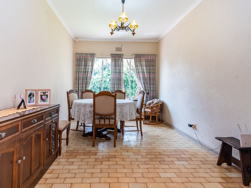 A dining room featuring tiled flooring, a central ceiling light fixture, and a window providing natural light.