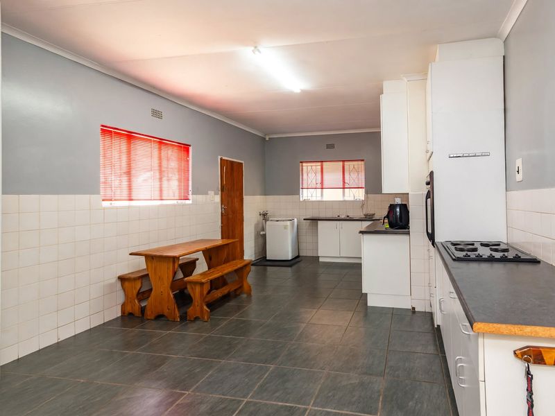 Functional kitchen featuring tiled flooring, built-in cabinetry, gas hob, and oven, with a dedicated laundry area and ample space for a dining set.