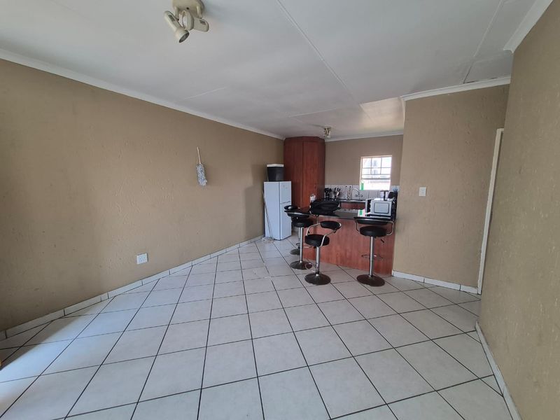 Open plan living and kitchen area featuring tiled flooring, a breakfast bar, and functional kitchen cabinetry.
