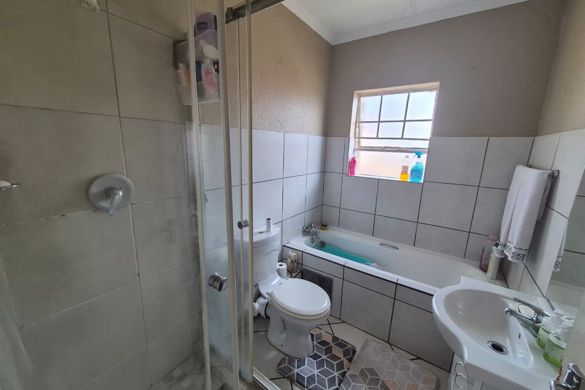 A functional bathroom featuring a separate shower enclosure, bathtub, toilet, and pedestal basin with tiled finishes throughout.