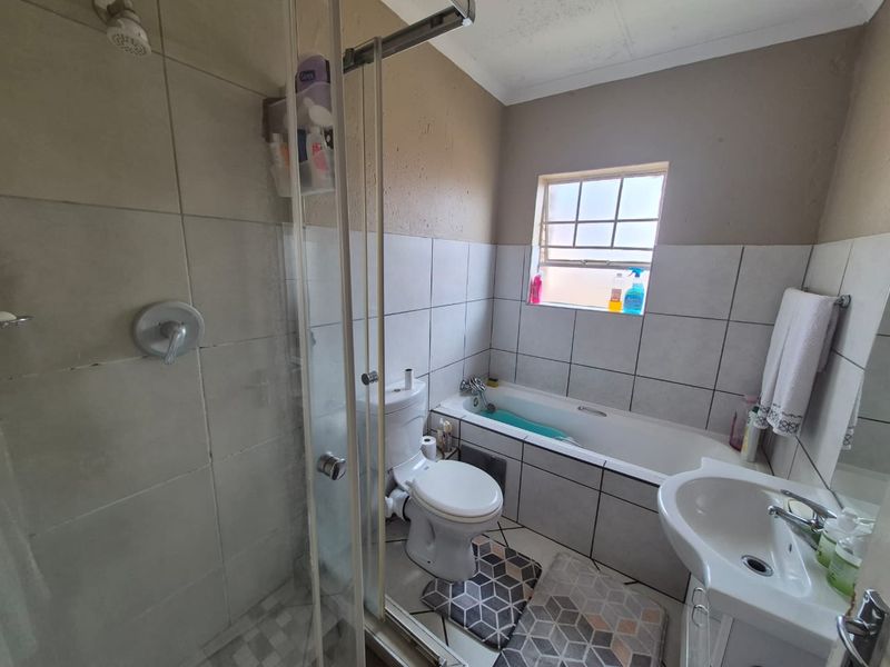 A functional bathroom featuring a separate shower enclosure, bathtub, toilet, and pedestal basin with tiled finishes throughout.