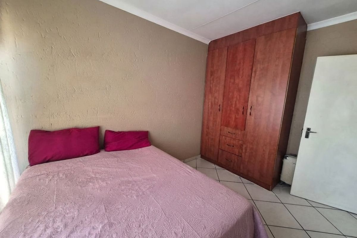 A bedroom featuring tiled flooring, a built-in wooden wardrobe, and coved ceiling details.