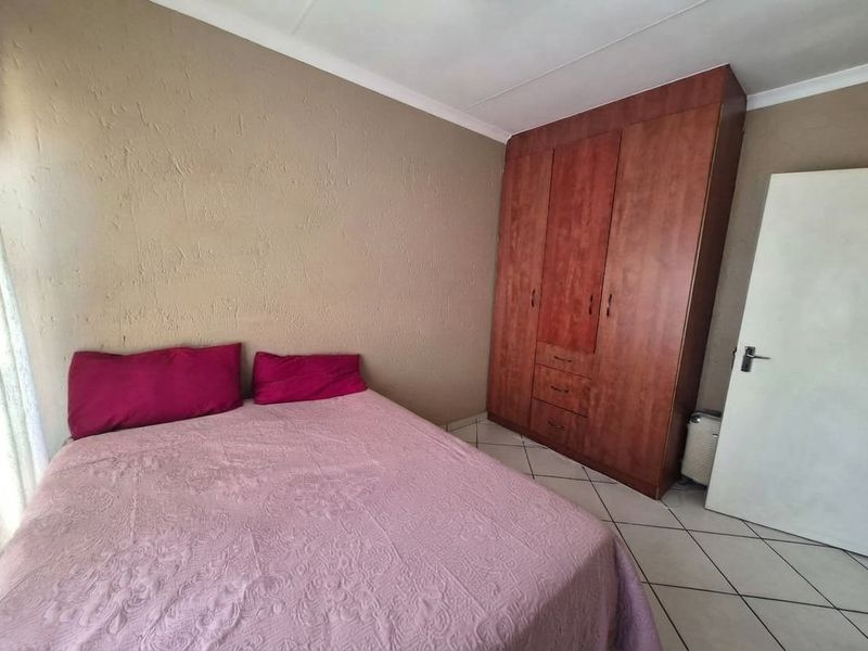 A bedroom featuring tiled flooring, a built-in wooden wardrobe, and coved ceiling details.