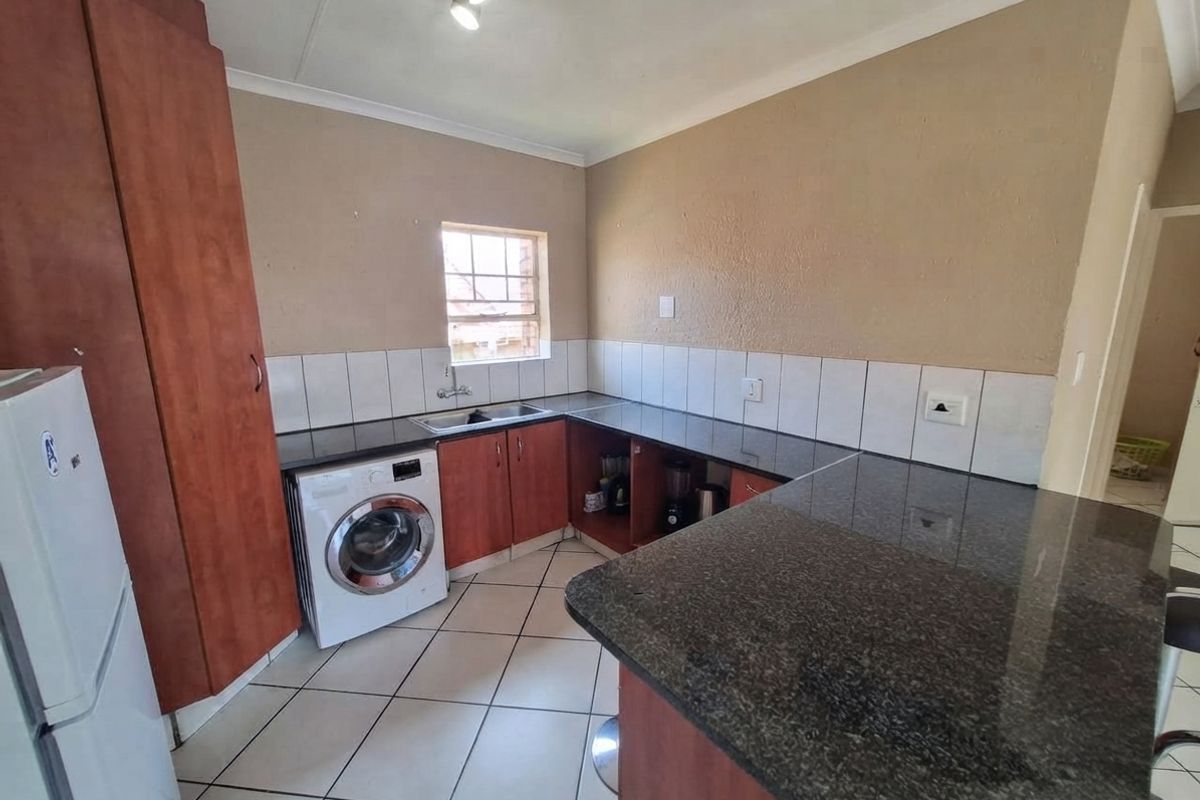 A functional kitchen featuring granite countertops, built-in wooden cabinetry, tiled flooring, and a tiled backsplash, providing a practical workspace for daily needs.
