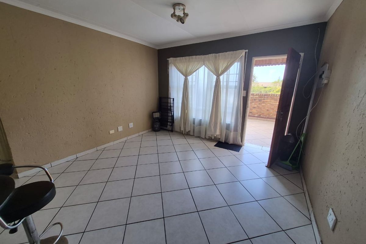 An empty living room featuring tiled flooring, neutral wall tones, and direct access to an outdoor patio area through a sliding glass door.