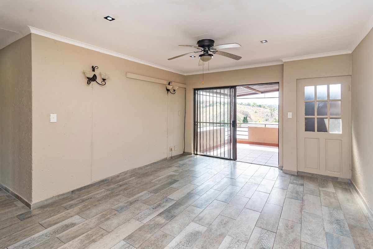 An empty living room featuring modern wood-look tile flooring, a ceiling fan, recessed lighting, and direct access to an outdoor patio area.
