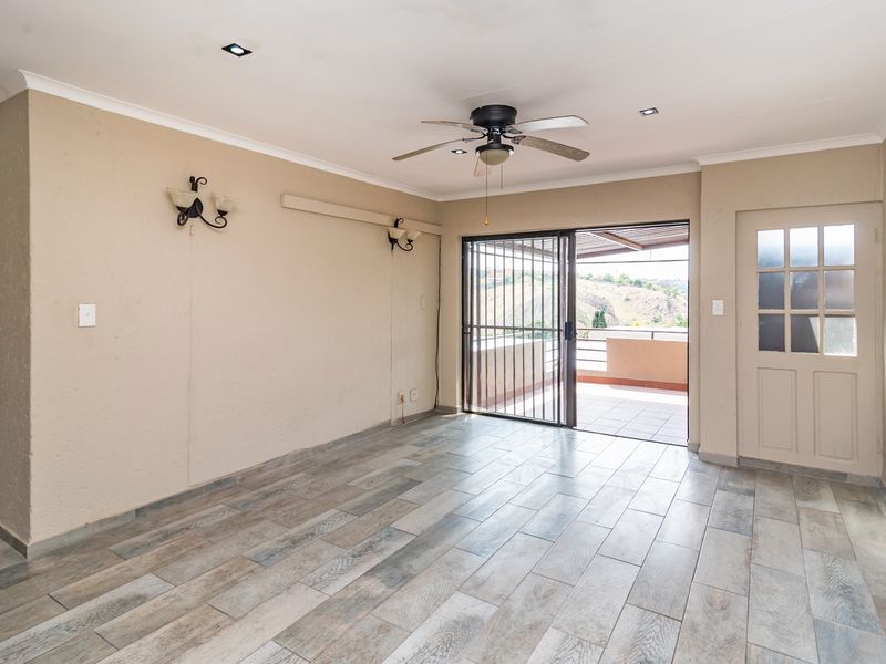 An empty living room featuring modern wood-look tile flooring, a ceiling fan, recessed lighting, and direct access to an outdoor patio area.