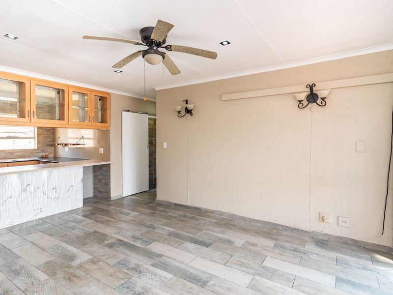 An open-plan living and kitchen area featuring tiled flooring, recessed lighting, a ceiling fan, and built-in kitchen cabinetry with a stone-look counter.