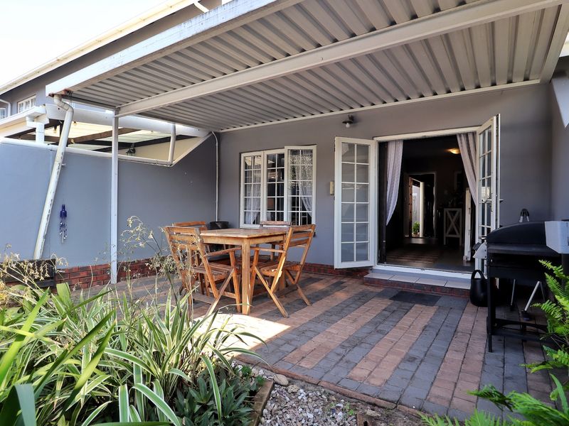 A covered patio area featuring paved flooring, a corrugated metal roof, and direct access to the interior through classic french doors.