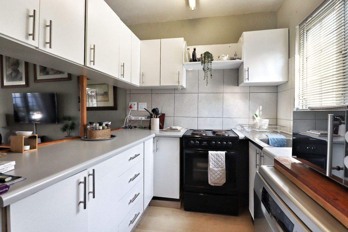 A functional kitchen featuring white cabinetry, tiled backsplash, laminate countertops, and a freestanding stove, offering a clean and practical workspace.