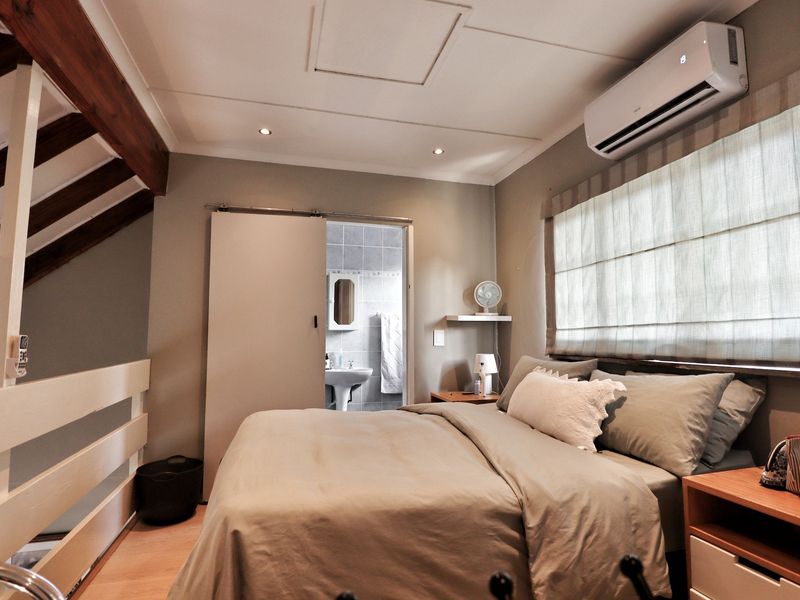 A well-maintained bedroom featuring exposed timber beams, split-system air conditioning, and direct access to an en-suite bathroom.