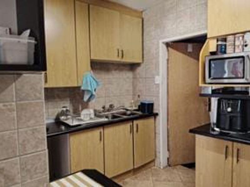 A functional kitchen featuring laminate cabinetry, tiled backsplash, and built-in microwave space, offering a practical layout with potential for modern cosmetic updates.