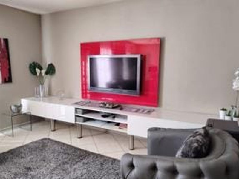 A living room featuring a modern, wall-mounted media console with a high-gloss finish and tiled flooring.