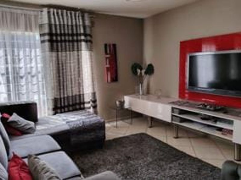 A living room featuring tiled flooring and a built-in media console with a red accent wall panel.