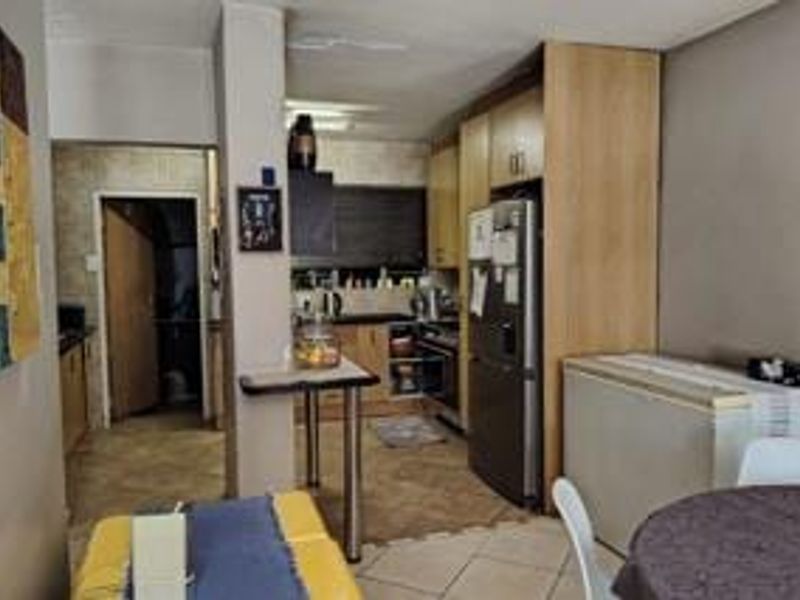 A functional kitchen featuring built-in cabinetry, laminate countertops, and a breakfast bar, seamlessly connected to the dining area with tiled flooring throughout.
