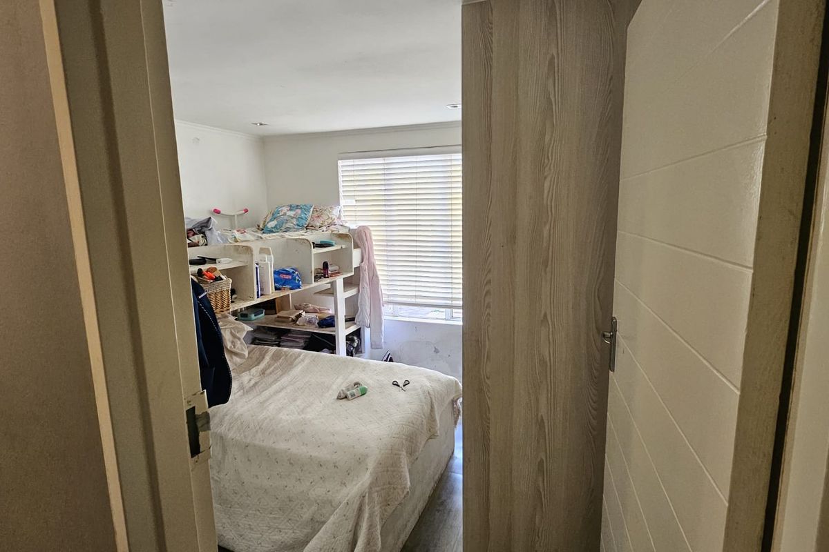 A bedroom featuring laminate flooring, recessed lighting, and a built-in cupboard, with visible wall surface damage near the window area.