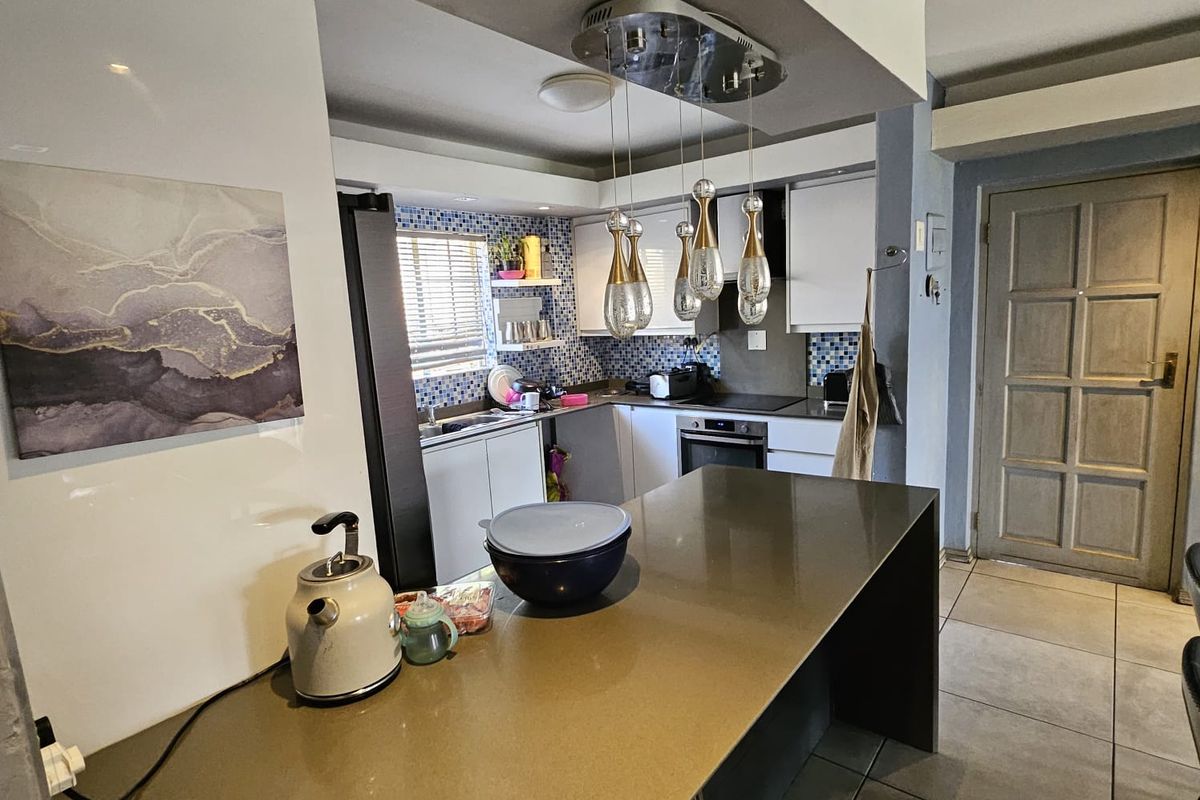 A functional kitchen featuring a breakfast bar, stone countertops, mosaic tile backsplash, built-in oven, and modern pendant lighting.