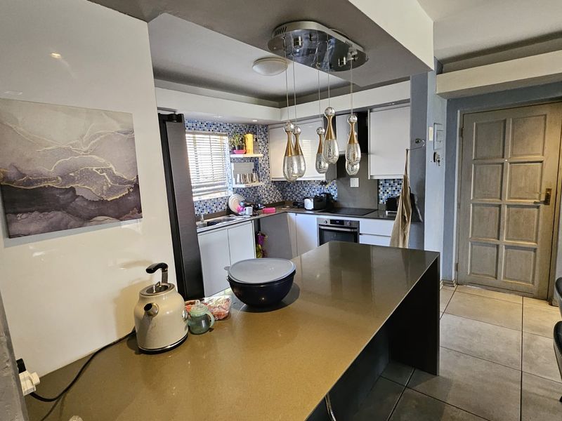 A functional kitchen featuring a breakfast bar, stone countertops, mosaic tile backsplash, built-in oven, and modern pendant lighting.
