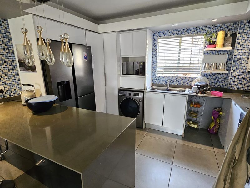 Modern kitchen featuring a stone island, mosaic tile backsplash, built-in cabinetry, and integrated appliances with tiled flooring throughout.