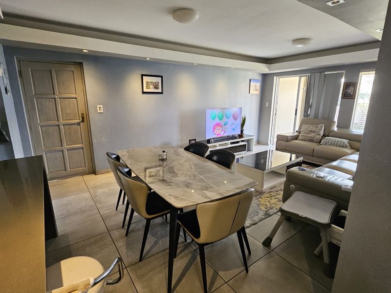 Open-plan living and dining area featuring large format floor tiles, a recessed ceiling design, and direct access to an outdoor patio through sliding doors.