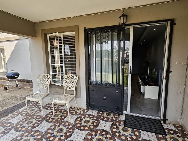 Covered patio area featuring decorative patterned floor tiles, a security gate, and direct access to the interior living space.