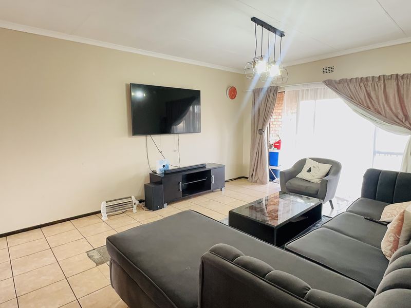 A living room featuring tiled flooring, a coved ceiling, and a sliding glass door providing access to the outdoor area.