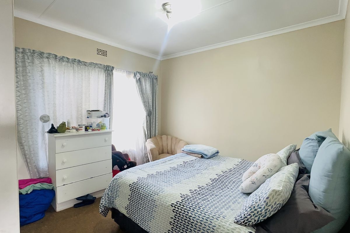 A standard bedroom featuring neutral wall finishes, a ceiling cornice, and a ventilation grille, providing a functional space for rest.