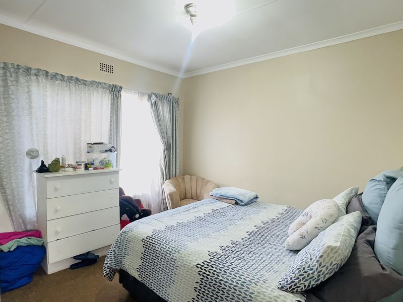 A standard bedroom featuring neutral wall finishes, a ceiling cornice, and a ventilation grille, providing a functional space for rest.